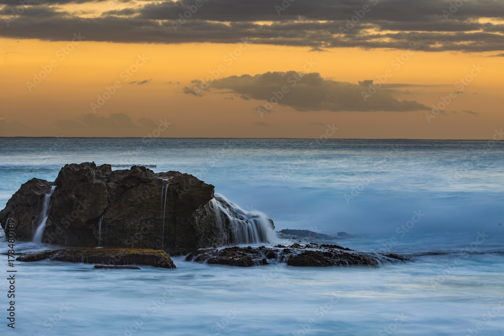 波涛汹涌的海水中的深色岩石，日落时长时间曝光拍摄