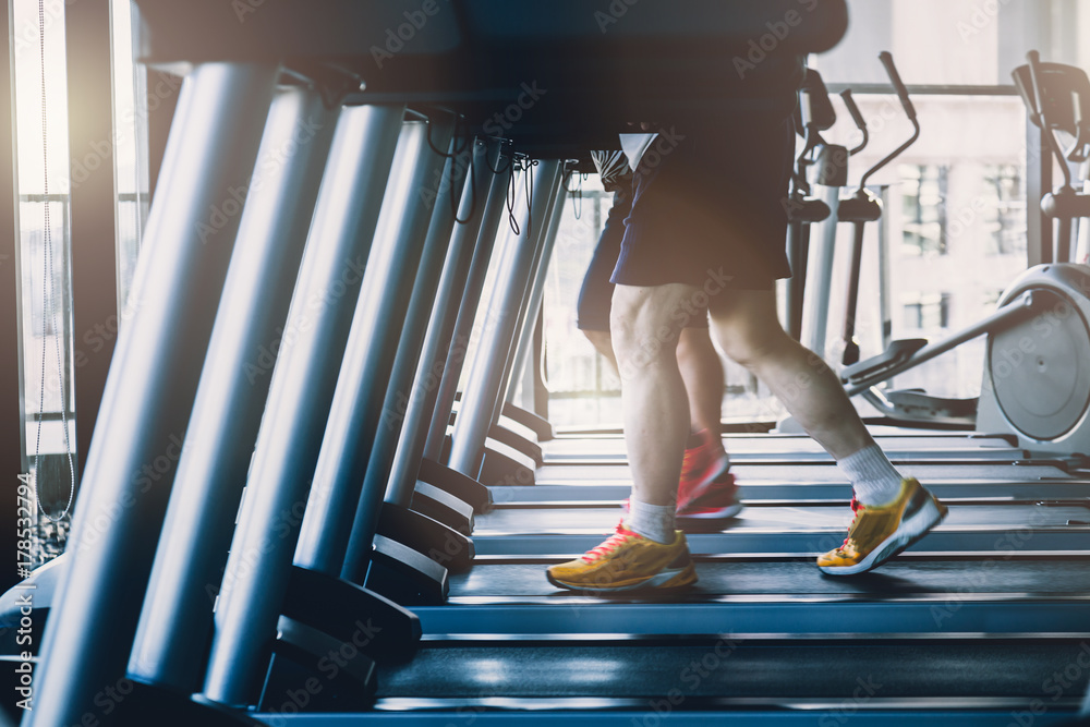 健康的男人和女人在健身房的跑步机上跑步。运动与健康概念