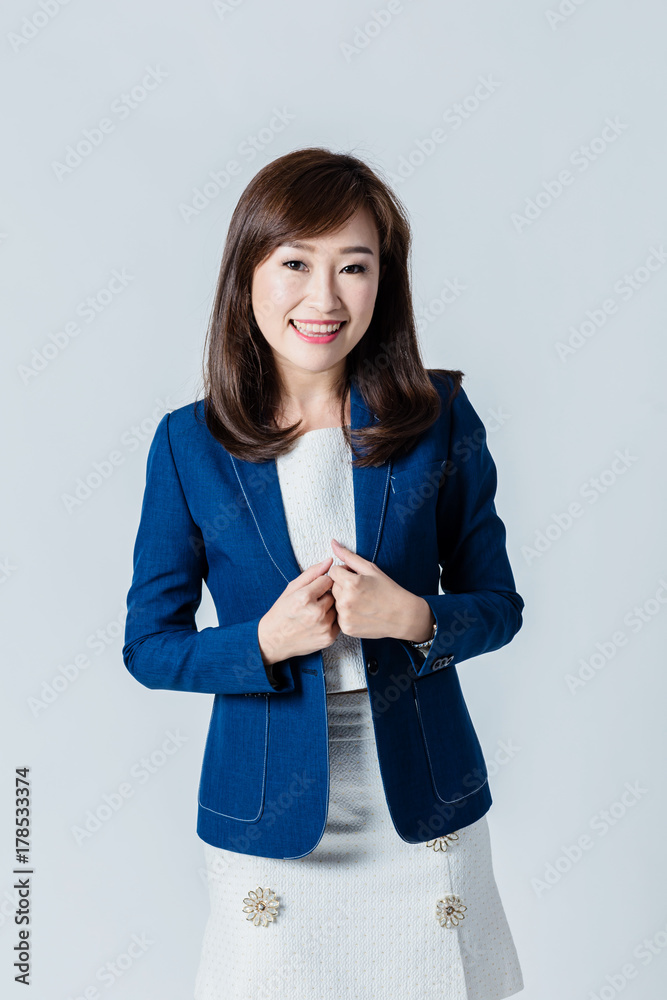 穿着蓝色西装的亚洲女性在工作室里摆出幸福的动作姿势，隔离白色背景