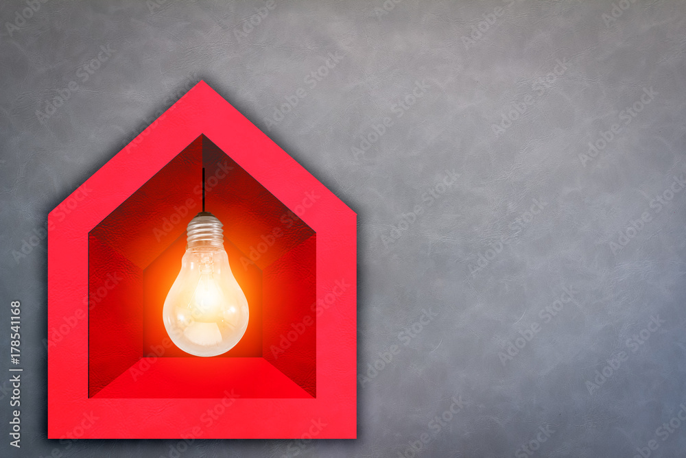创业理念和创意理念。带发光灯泡的红色纸屋模型，灰色皮革b