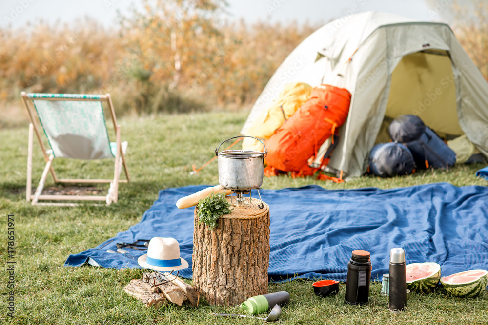 户外绿色草坪上有帐篷、背包、椅子和徒步旅行设备的露营地
