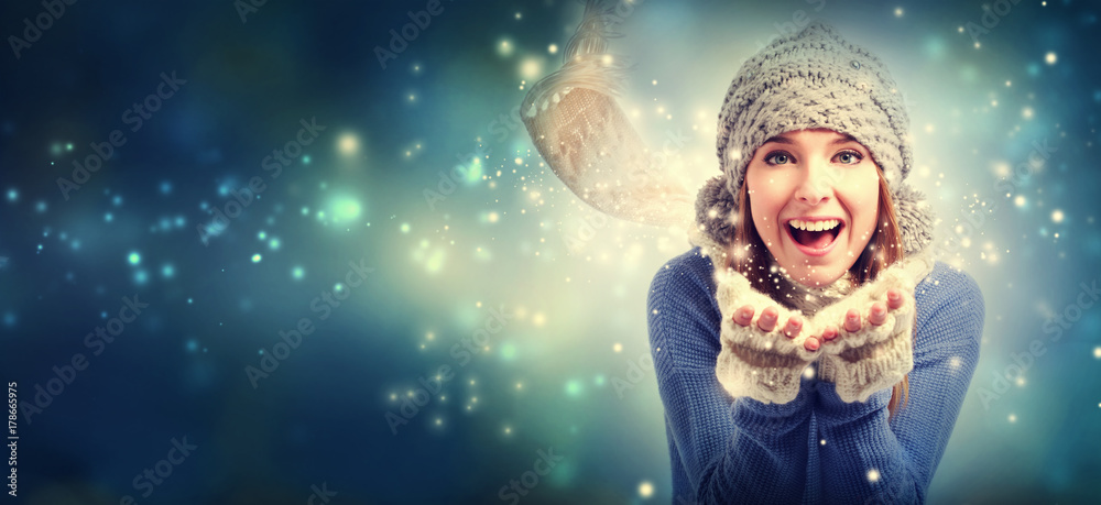 快乐的年轻女子在雪夜吹雪