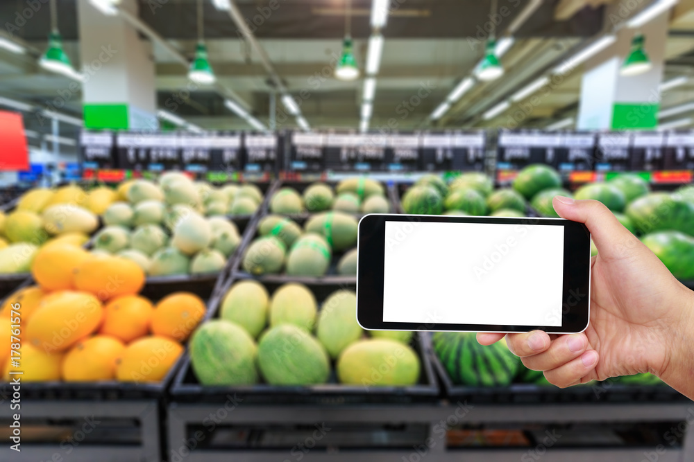 白色空白屏幕、超市水果背景模糊的手持智能手机