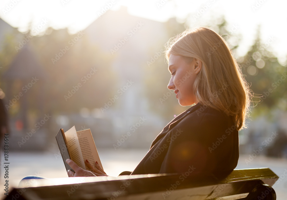 日落时分，年轻女孩在城市街道上看书