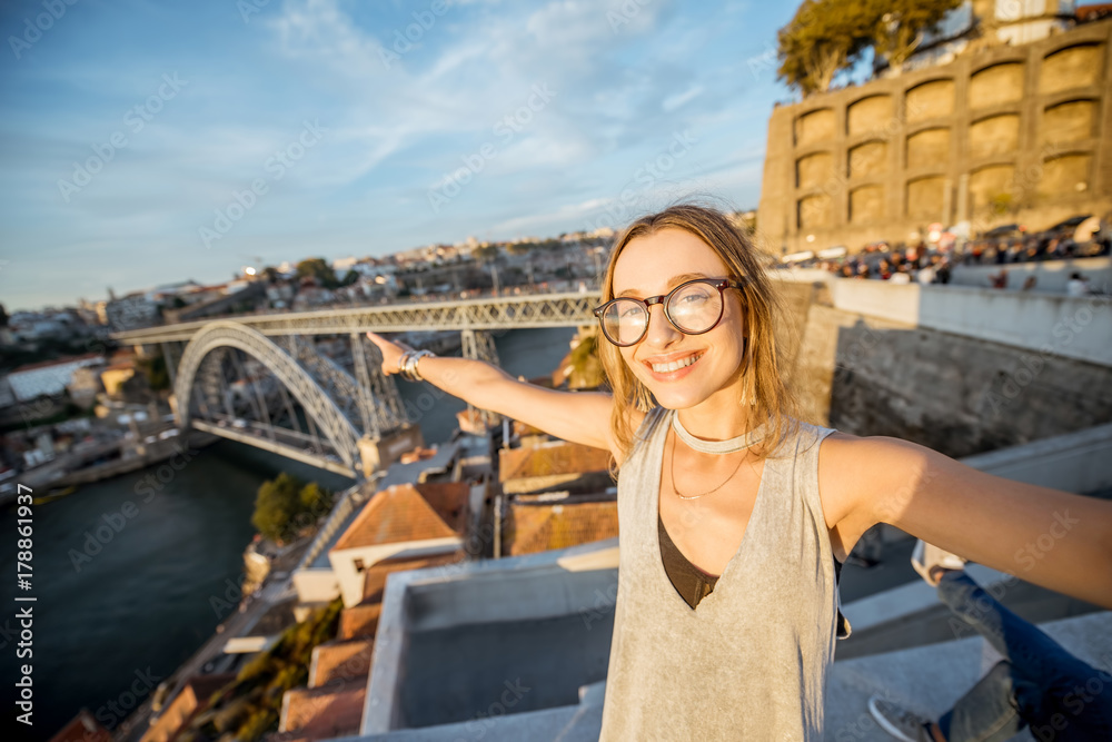 Young woman tourist making selfie photo on the beautiful cityscape background during the sunset in P