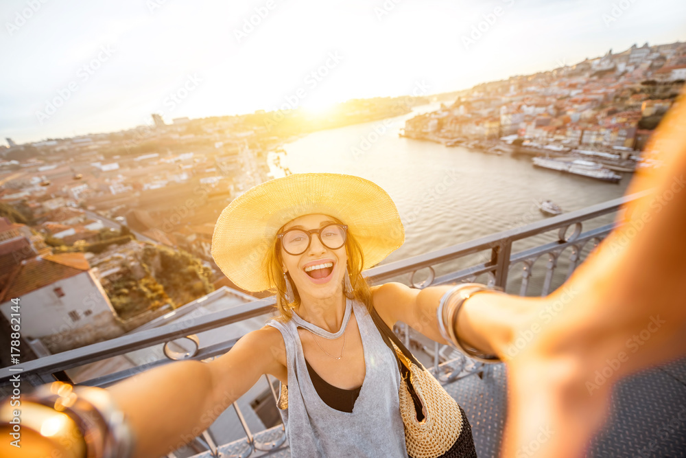 年代，戴着太阳帽的年轻女游客在美丽的城市景观背景下自拍