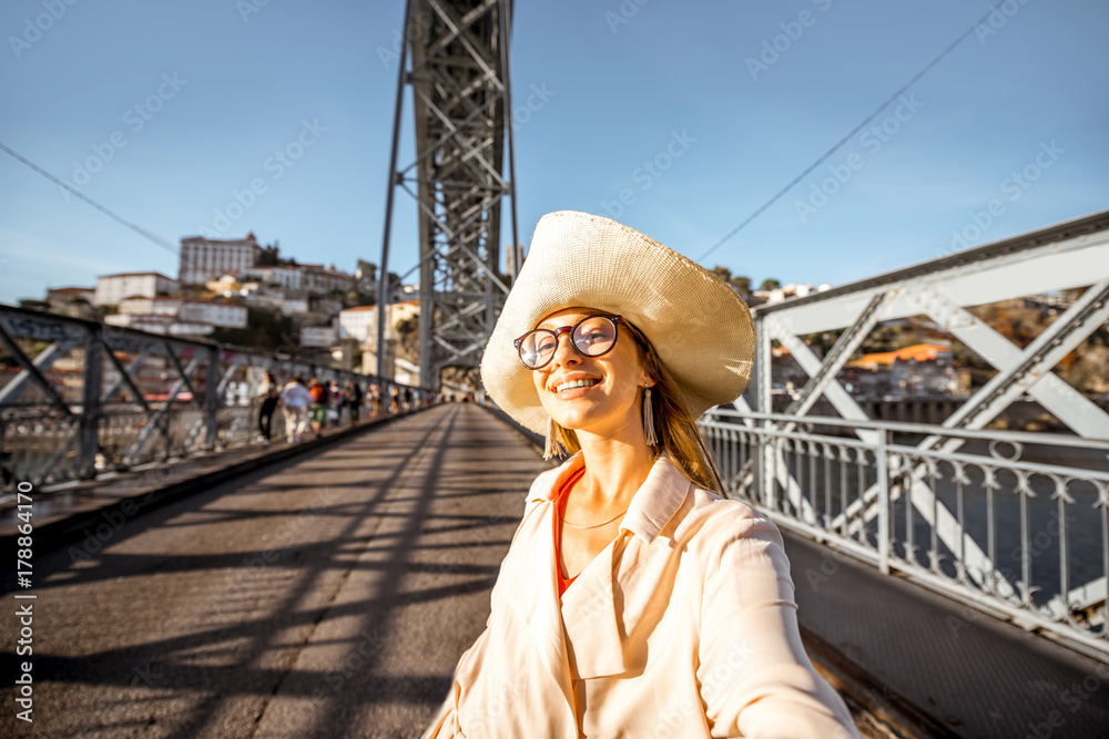 Young woman tourist making selfie photo on the famous Luis bridge during the sunny day in Porto city