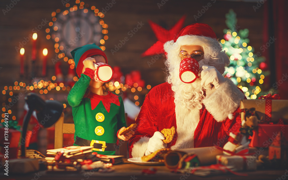 圣诞节。圣诞老人和小精灵一起喝牛奶吃饼干
