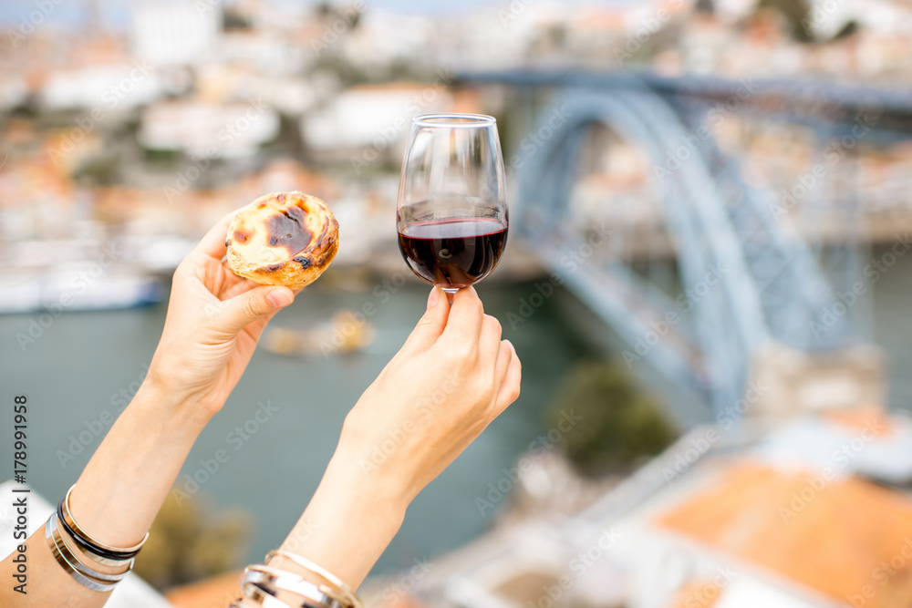 拿着一杯红酒，配上一种名为pastel de Nata的传统葡萄牙甜点。