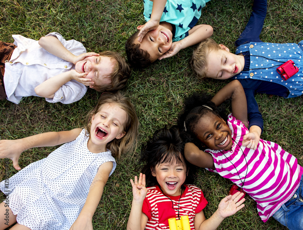 一群幼儿园的孩子躺在公园的草地上，微笑着放松