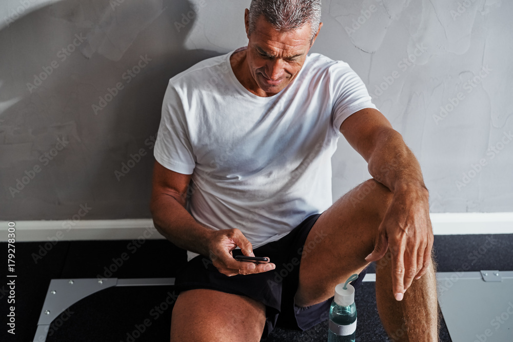 Mature man checking his cellphone after a work out