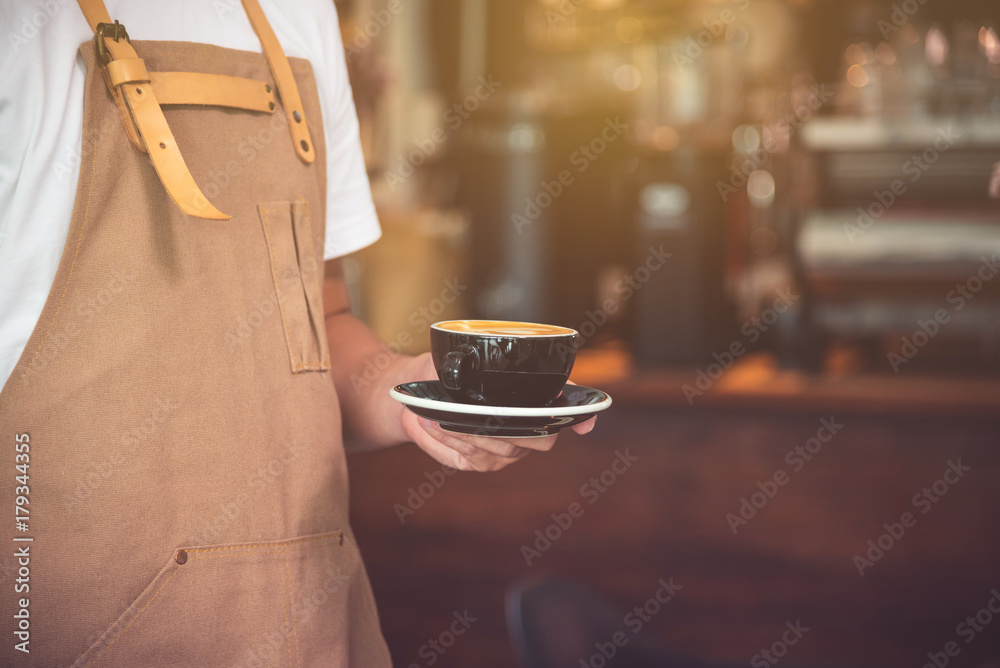 咖啡馆服务员端上一杯咖啡的手，配上老式的咖啡壶