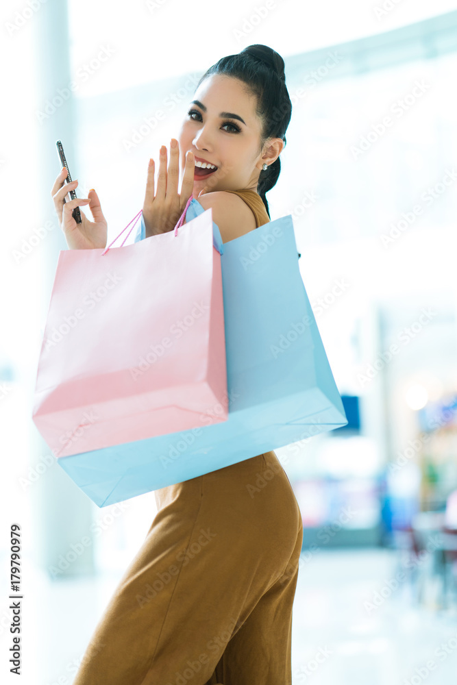 亚洲女孩在购物中玩得很开心。在购物中心里，她拿着购物袋。