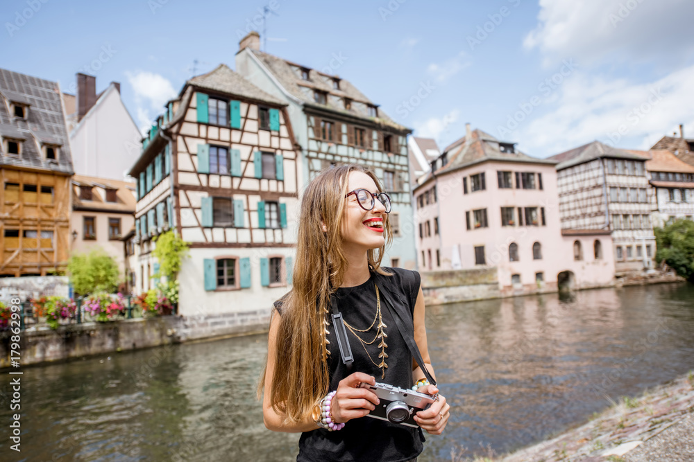 年轻的女游客拿着相机站在斯特拉美丽的老建筑和水道旁