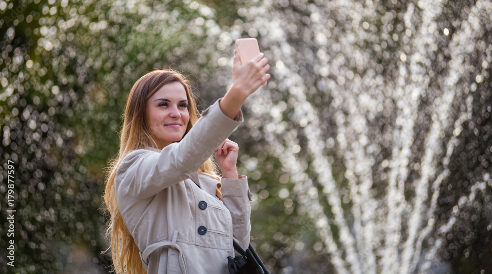 城市里快乐的女人在智能手机上拍照