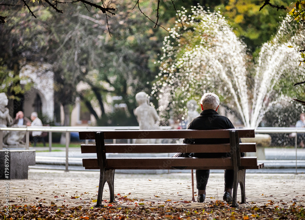 沮丧悲伤的老妇人独自坐在公园的长椅上