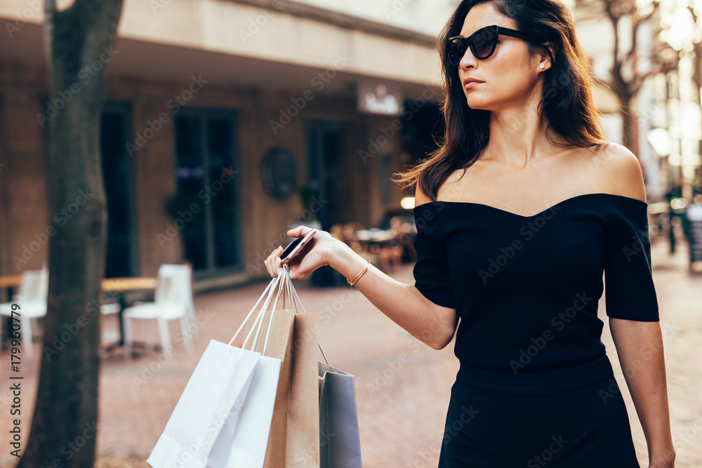 时尚女人提着购物袋走在街上
