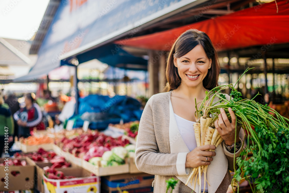 微笑的女人在绿色市场买菜的画像。