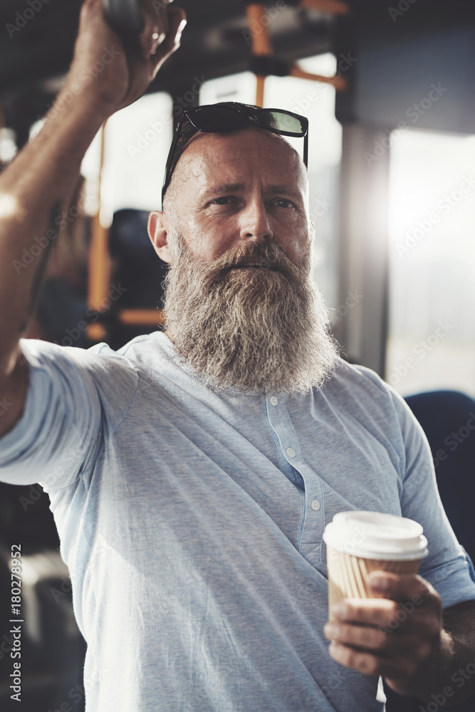 留着胡子、喝着咖啡的成熟男人坐公交车