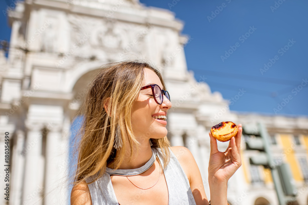 年轻女子在凯旋门上拿着一种叫做pastel de Nata的葡萄牙蛋挞糕点