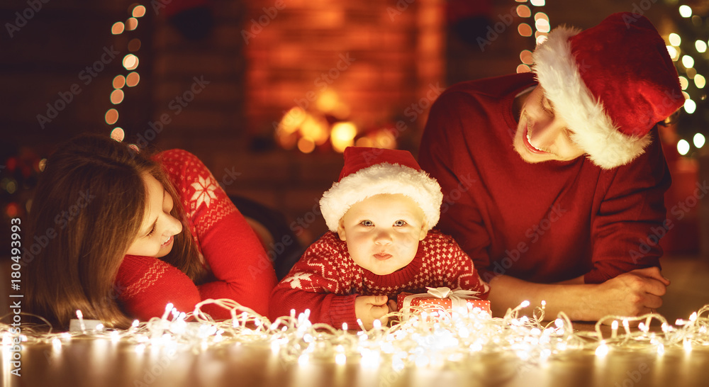 幸福的家庭母亲父亲和婴儿在家的圣诞树上