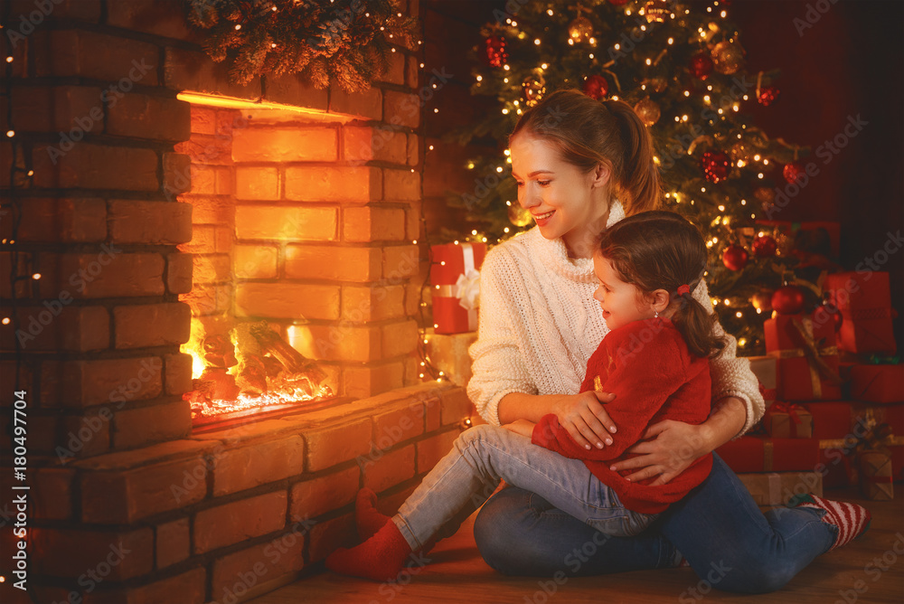 家庭母亲和孩子女儿在圣诞节看壁炉