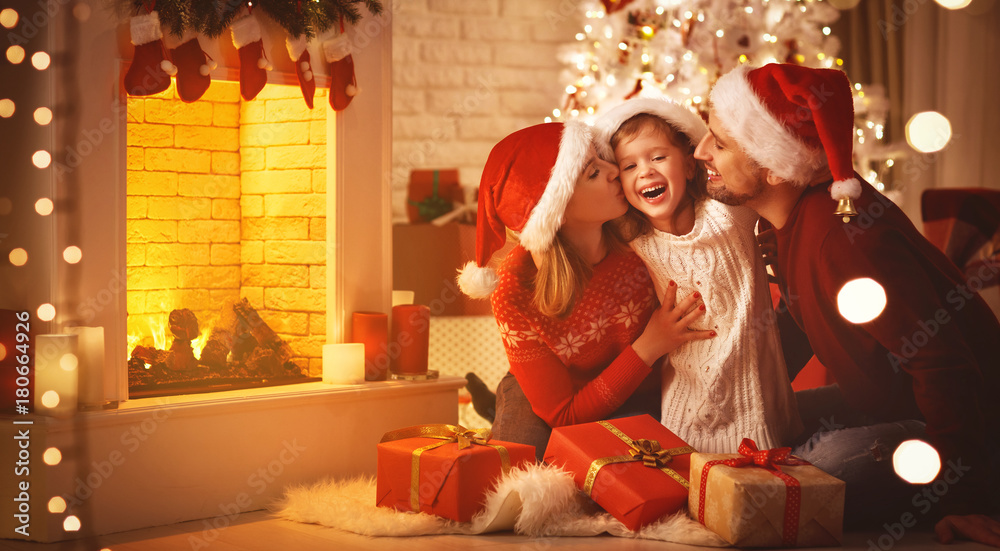 圣诞快乐！幸福的家庭母亲、父亲和孩子在树旁送礼物