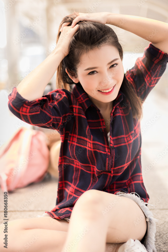美丽幸福的年轻亚洲女孩穿着休闲服独自在火车站或机场旅行