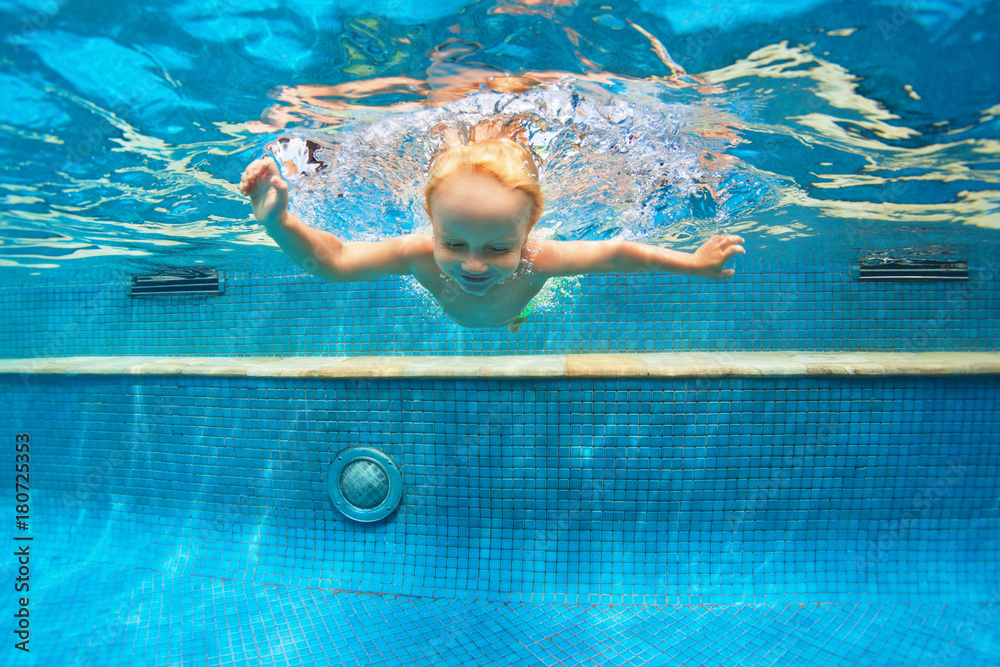 孩子学习游泳的有趣画像，在蓝色游泳池里有趣地潜水——跳到水下深处