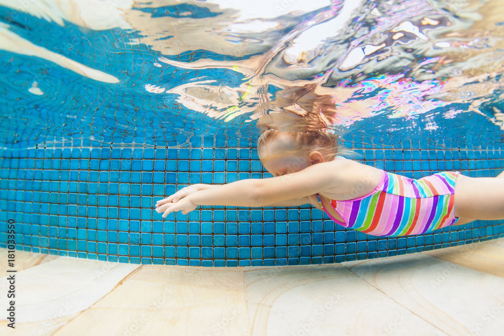 孩子学习游泳的有趣画像，在蓝色游泳池里有趣地潜水——跳到水下深处