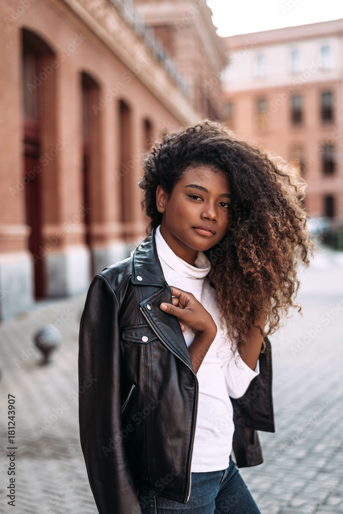 Portrait of attractive young woman in black leather jacket looking at camera.
