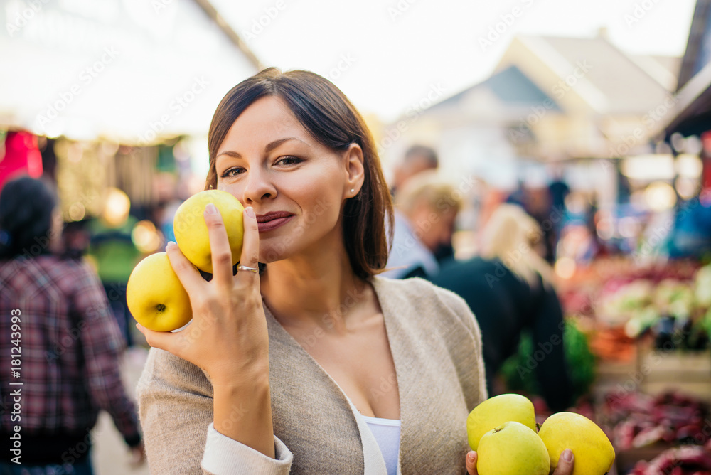 Woman in the fruit market with apples in hands.