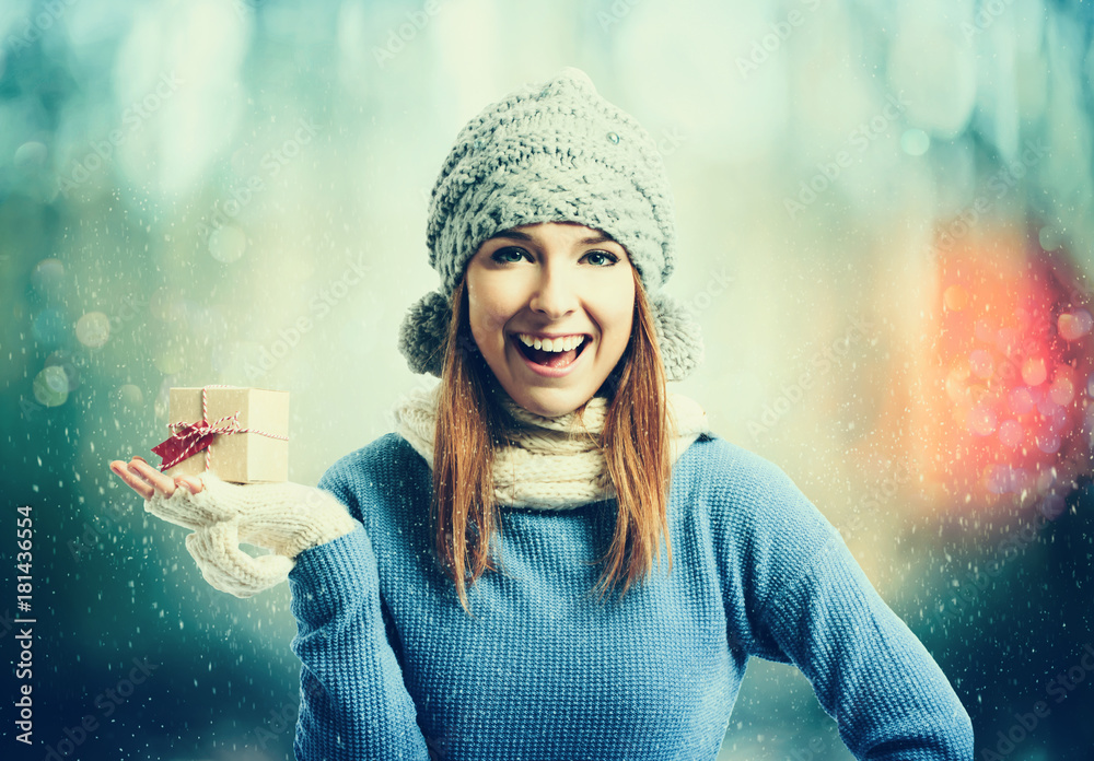 幸福的年轻女人在雪夜拿着礼物盒
