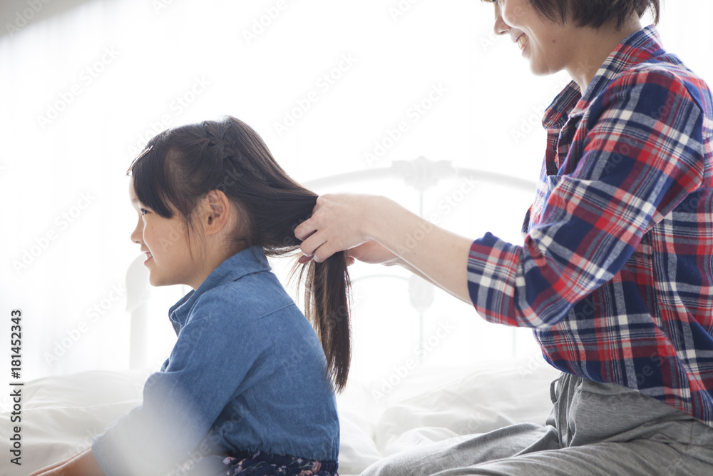 在卧室里，一位年轻的母亲正在给女儿们系头发。
