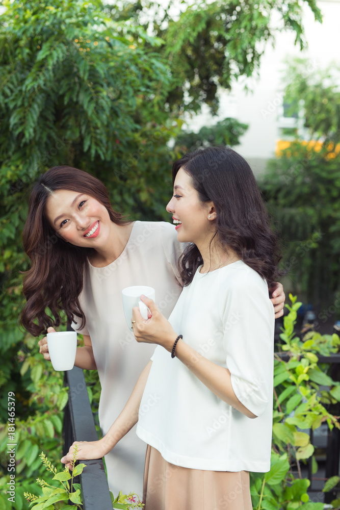 美丽的亚洲女性朋友在阳台上拿着一杯冰黑咖啡