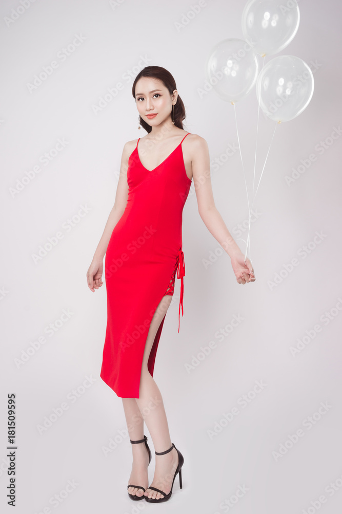 亚洲美女身穿红色连衣裙，带着柔和的气球，抬头仰望