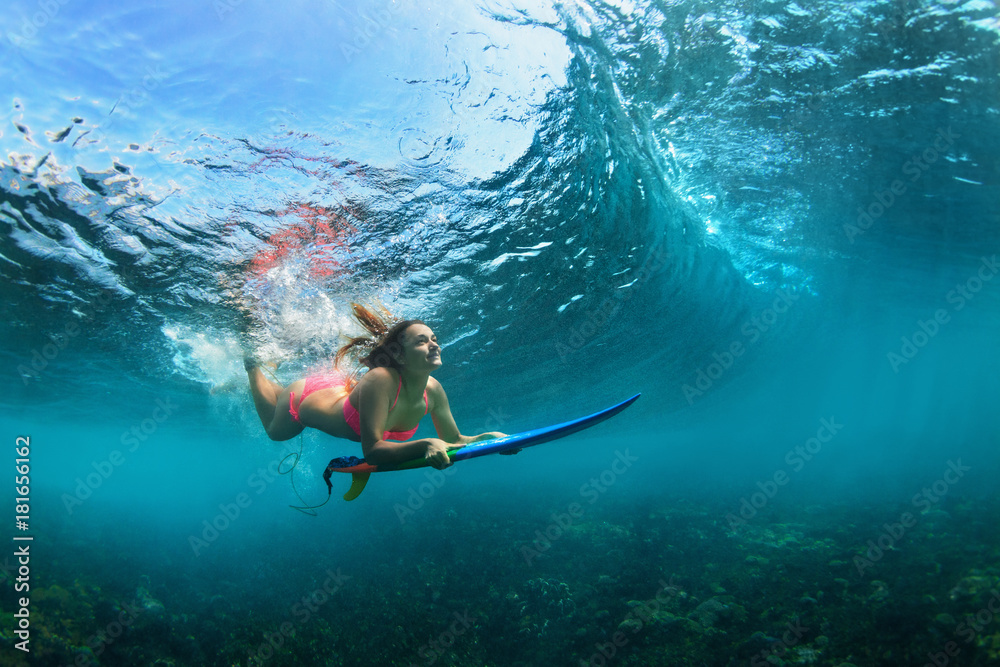 活跃的比基尼女孩在行动。冲浪板冲浪的女人在巨大的波浪下潜入水下