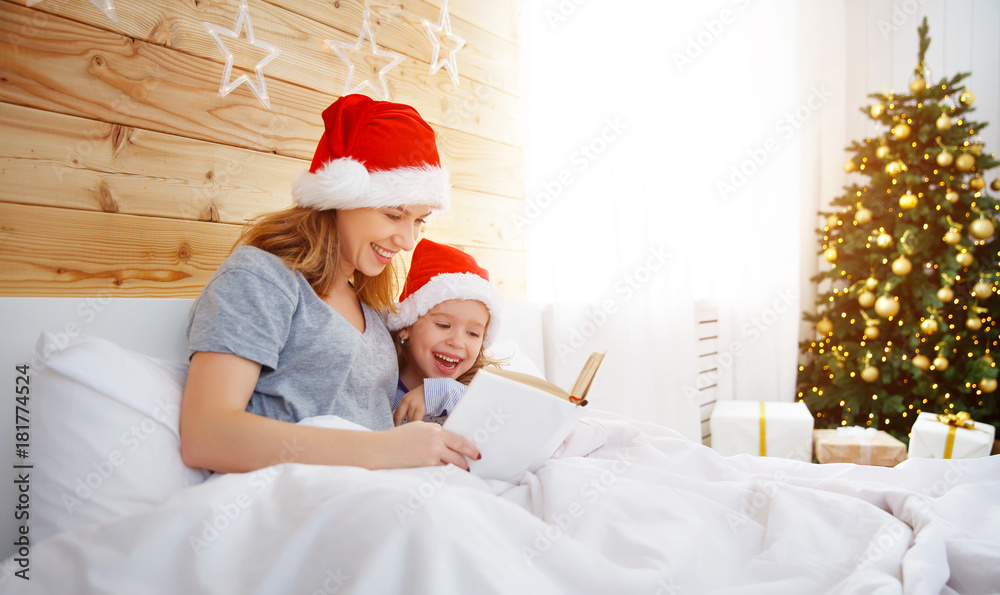 圣诞节早上，家庭母亲在床上给孩子读书。