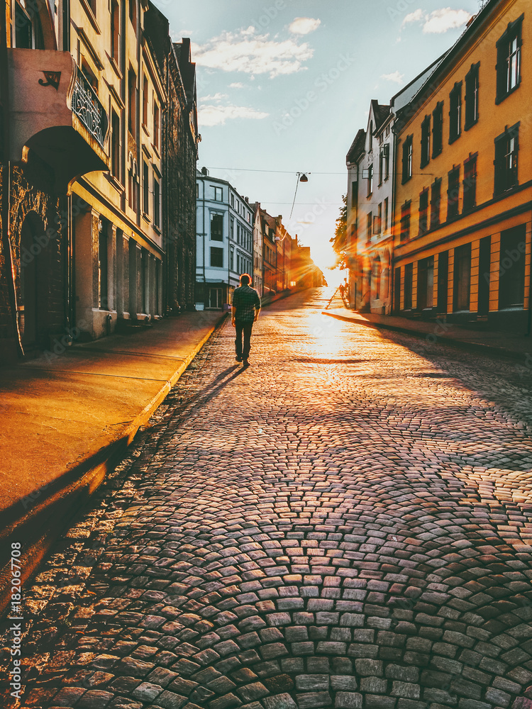 男子游客走在日落的街道上旅行生活方式概念度假鹅卵石路Alesund cit