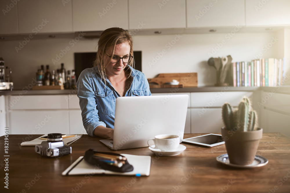女企业家坐在厨房里用笔记本电脑工作