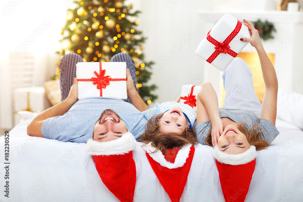 快乐的家庭母亲父亲和孩子在床上的圣诞节早晨