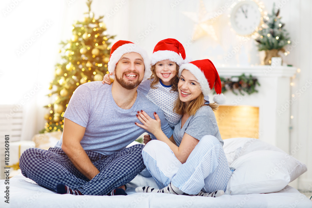 幸福的家庭母亲父亲和孩子在圣诞节早上躺在床上