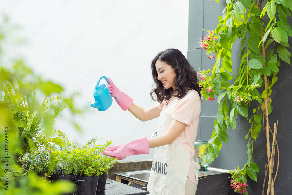 美丽的亚洲女园丁给植物浇水