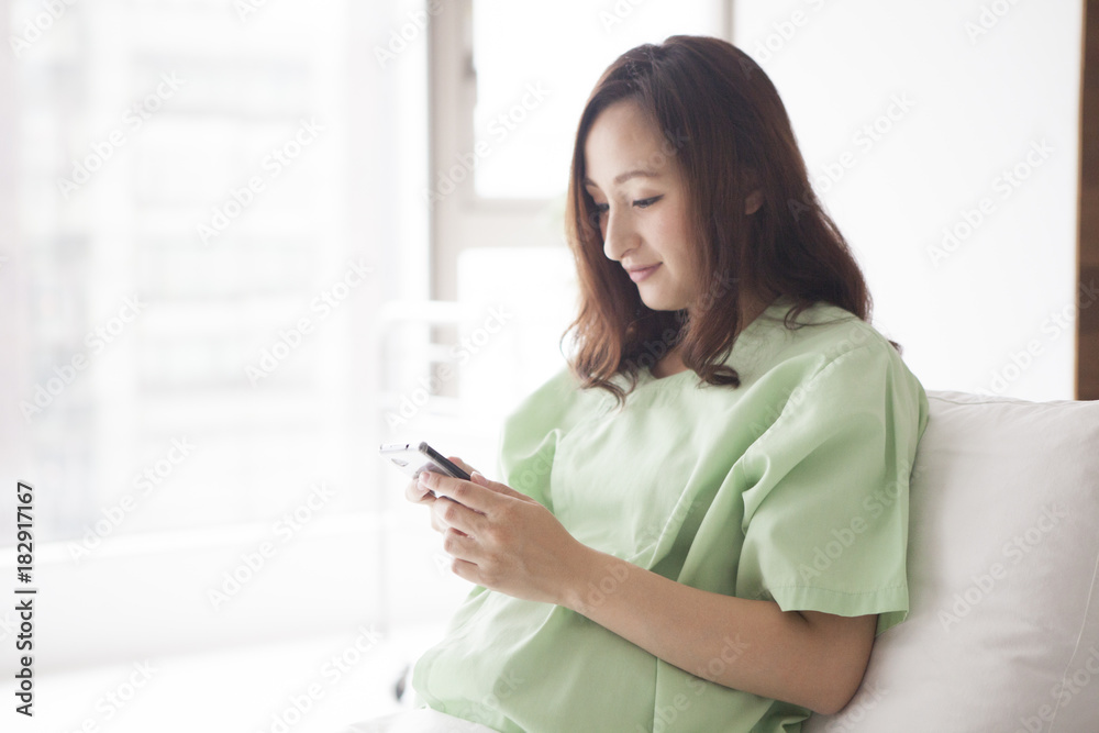 孕妇在医院房间里使用智能手机