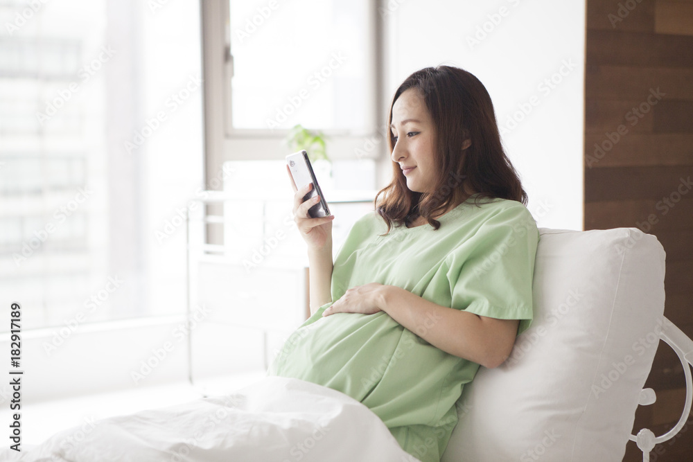孕妇在病房使用智能手机