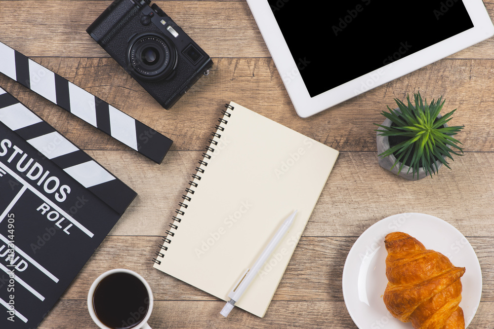 木桌上有电影拍板、数字桌、咖啡杯、钢笔和记事本的办公用品