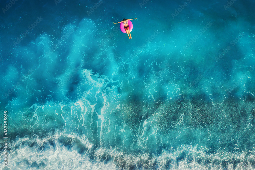 年轻女子在粉色环上游泳的鸟瞰图