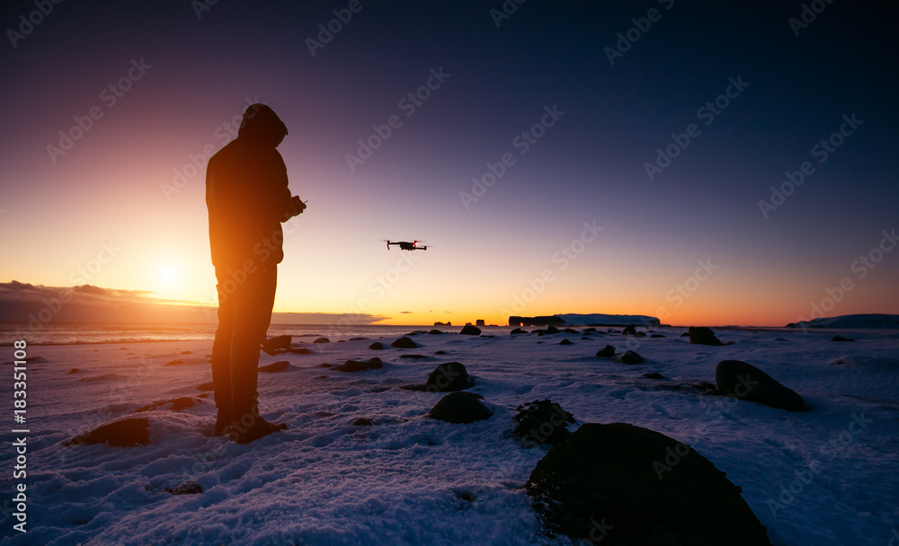 无人机飞行员与无人驾驶飞机在美丽的日落中。现代技术和户外活动