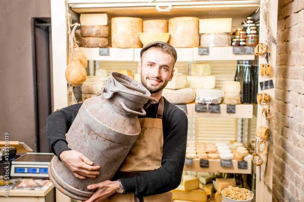 一个拿着大奶桶的奶酪小贩站在奶酪店里的画像