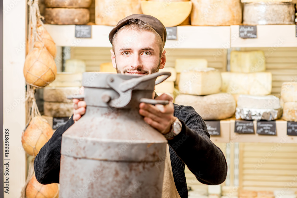 Portrait of a cheese seller with big dairy bucket standing in the cheese shop